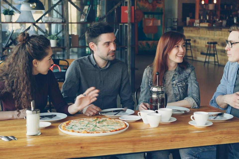 Friends are sharing pizza and conversation at a restaurant