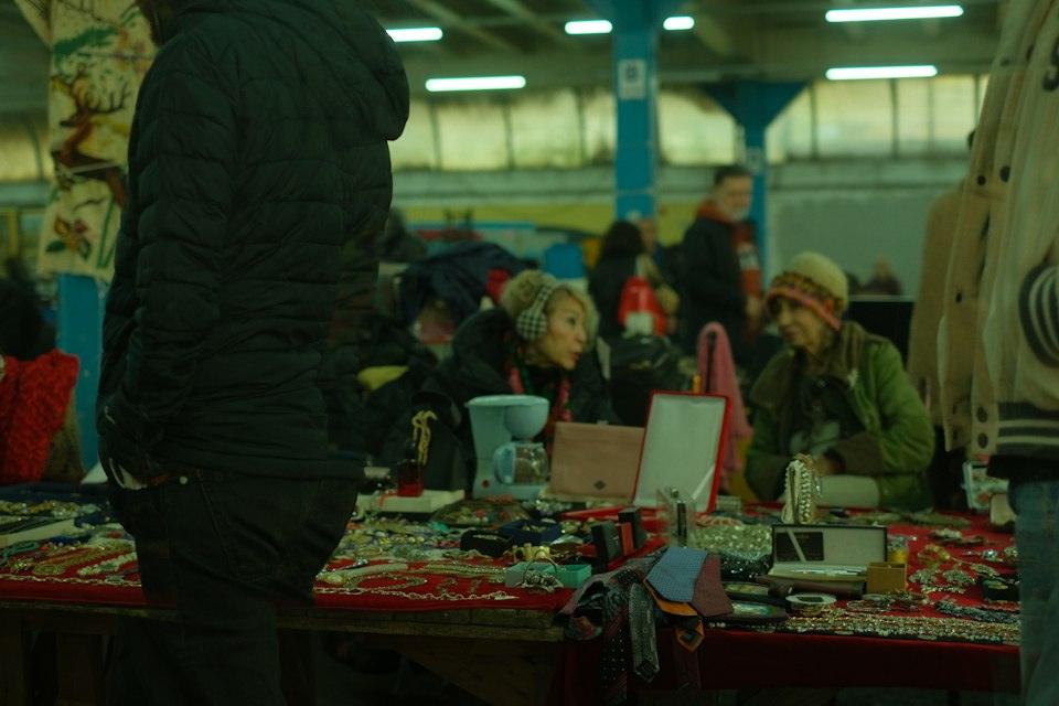 People browsing jewelry and accessories on a red cloth table