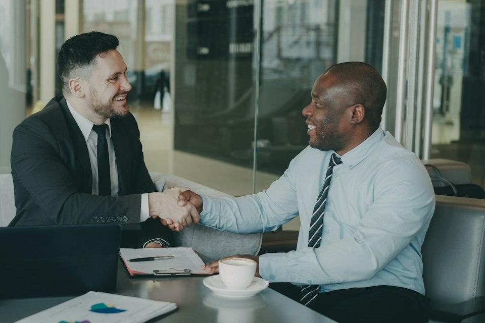 Two businessmen shaking hands across a table