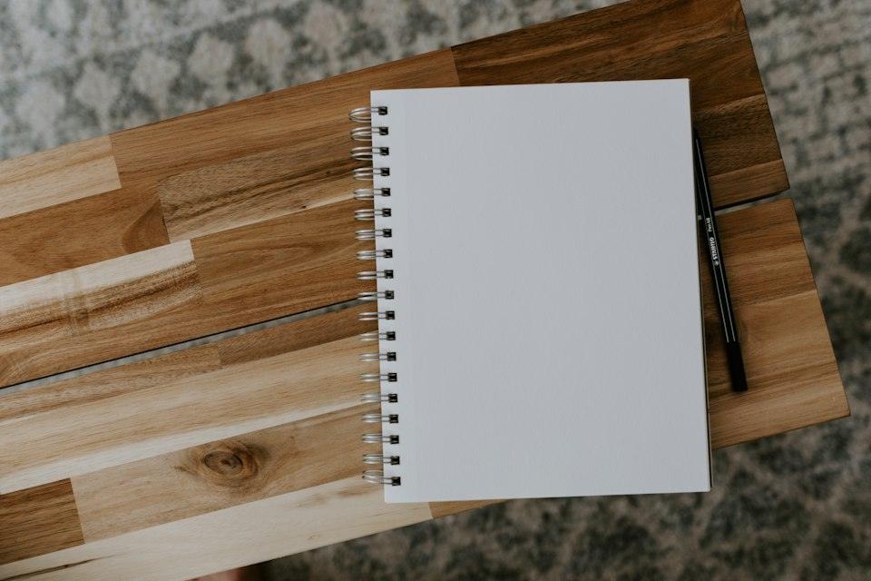 White spiral notebook on brown wooden table