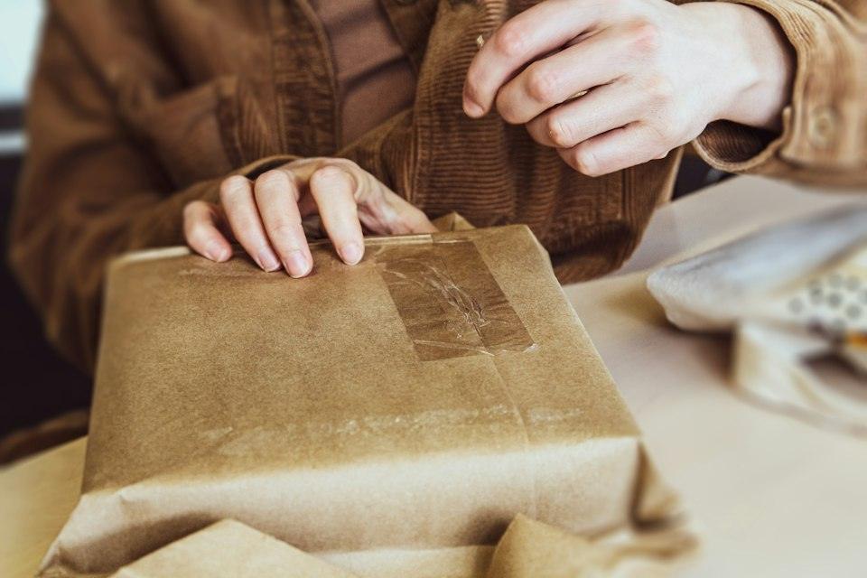 A person holding a brown paper bag on top of a table